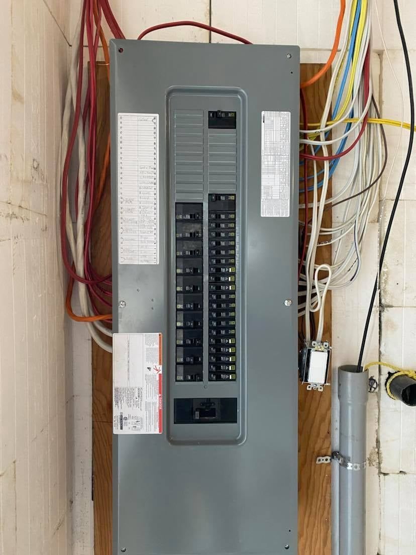 Un panneau électrique est accroché à un mur avec beaucoup de fils qui en sortent.