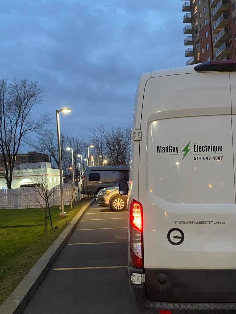 Une camionnette blanche est garée sur le bord de la route.