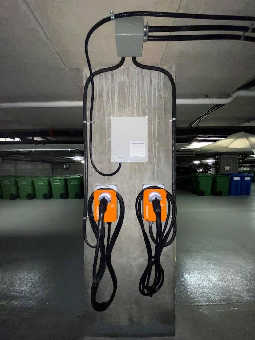 Deux bornes de recharge sont fixées à un pilier en béton dans un parking
