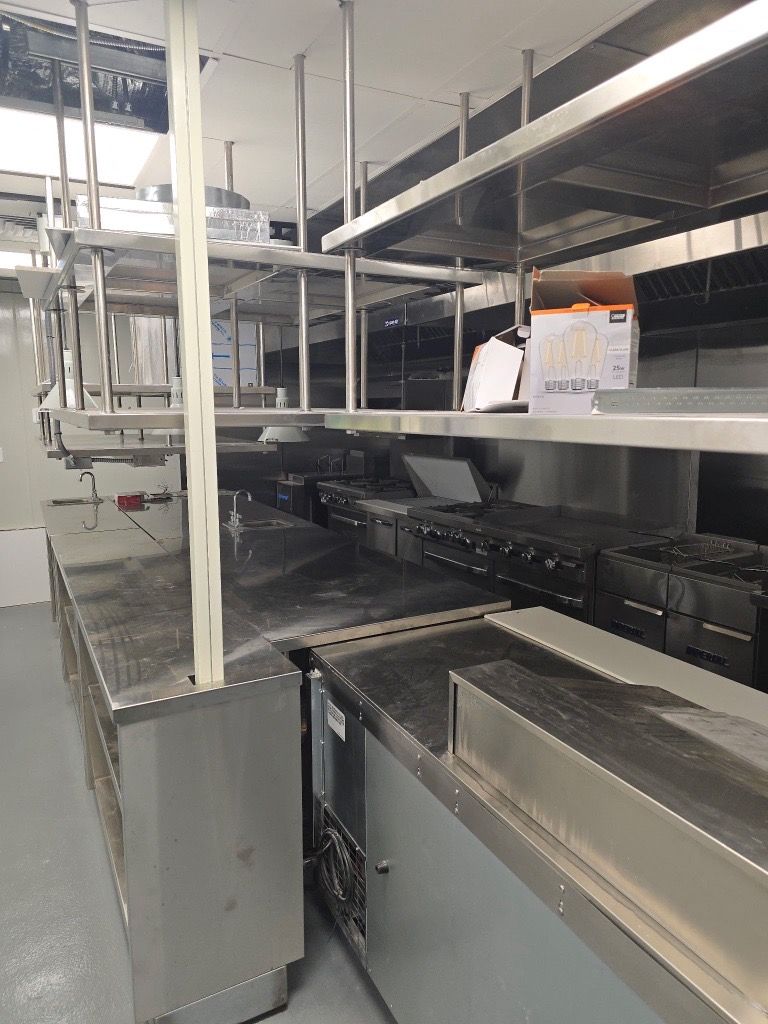 Commercial kitchen with stainless steel counters, shelving, and appliances.