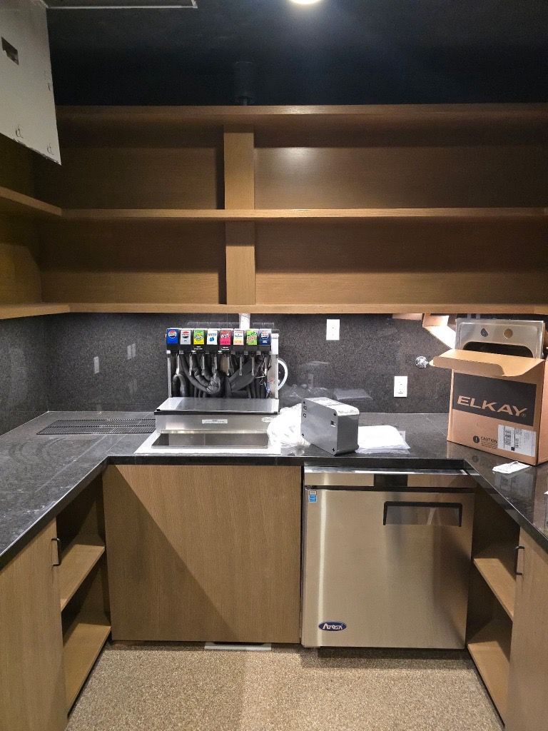 U-shaped kitchenette with stainless steel appliances, shelving, and a beverage dispenser.