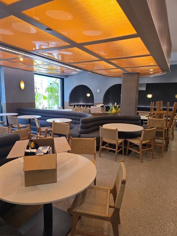 Restaurant interior: Round tables, wicker chairs, built-in curved seating, and a unique patterned ceiling.