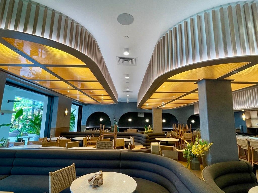 Interior of a restaurant with arched ceilings, tables, and seating. Gold accents, neutral tones.