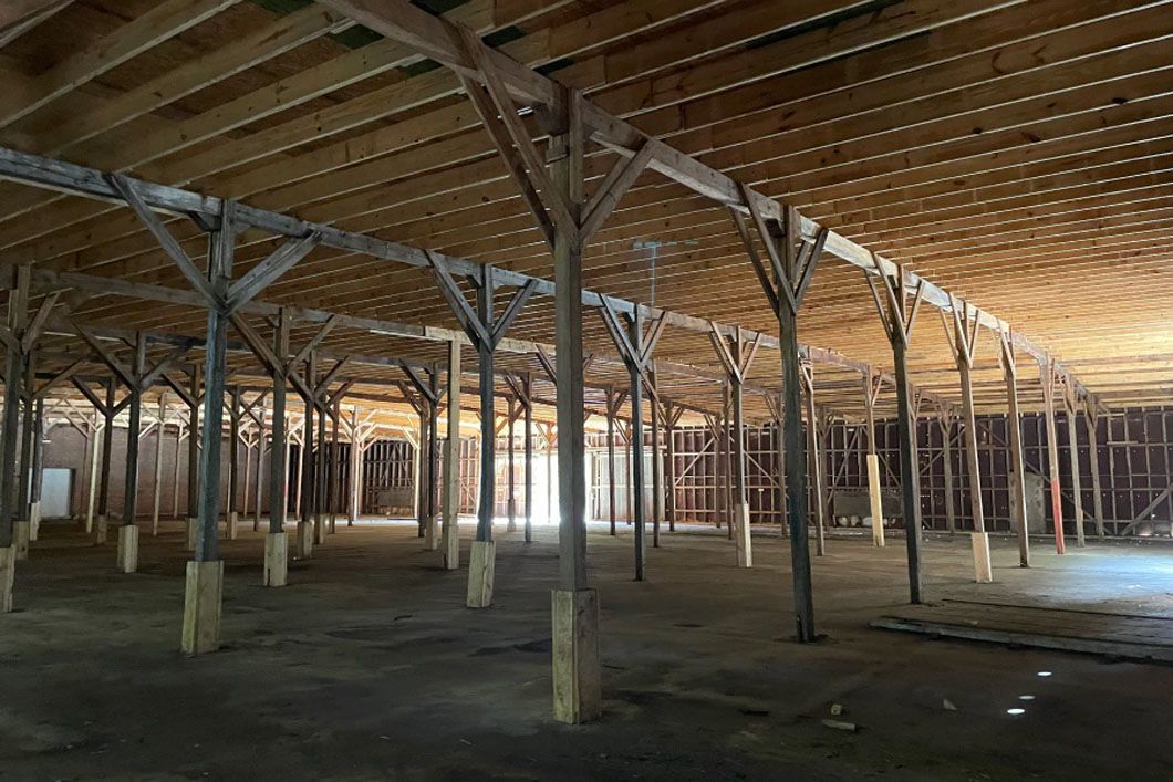 The inside of a large building under construction with a wooden roof.