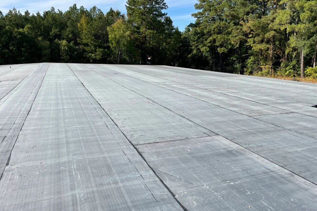 A large gray roof with trees in the background.