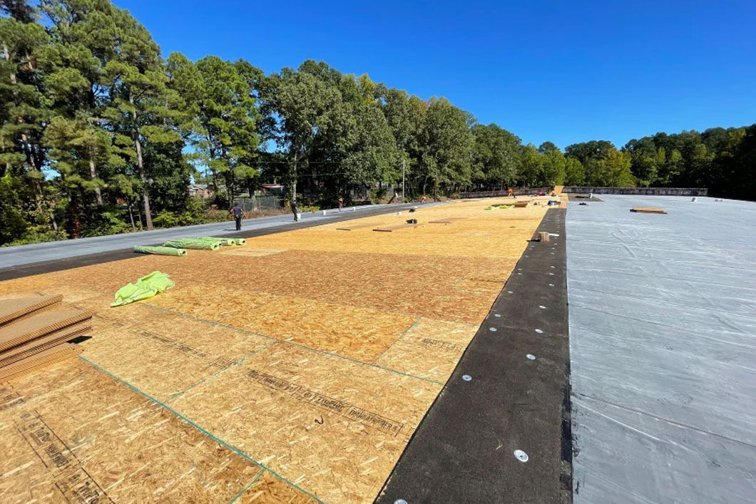 A roof is being built on a sunny day with trees in the background.
