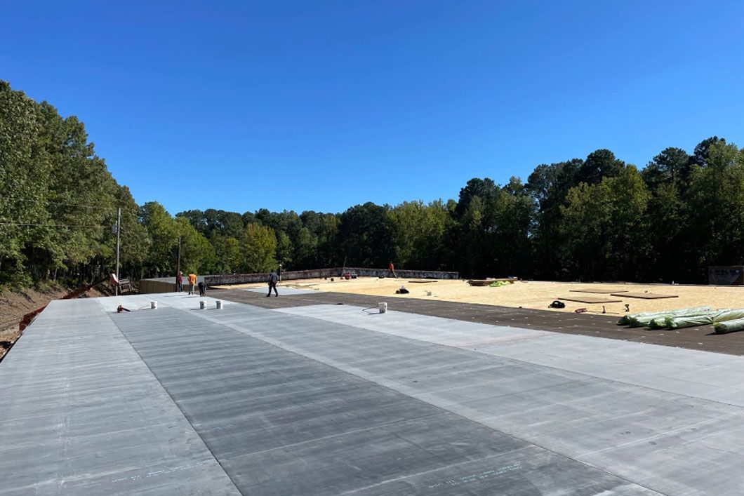 A concrete road is being built in a field with trees in the background.