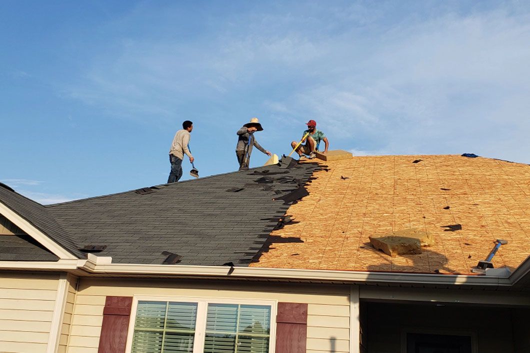 Two men are working on the roof of a house.