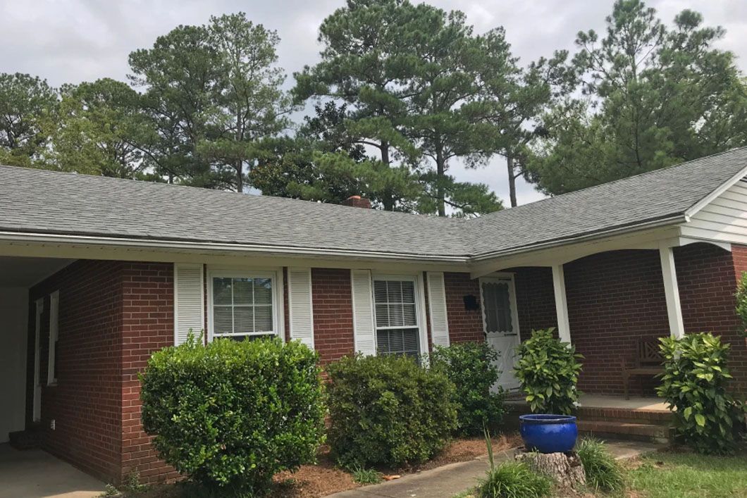 A brick house with a gray roof and a blue pot in front of it.