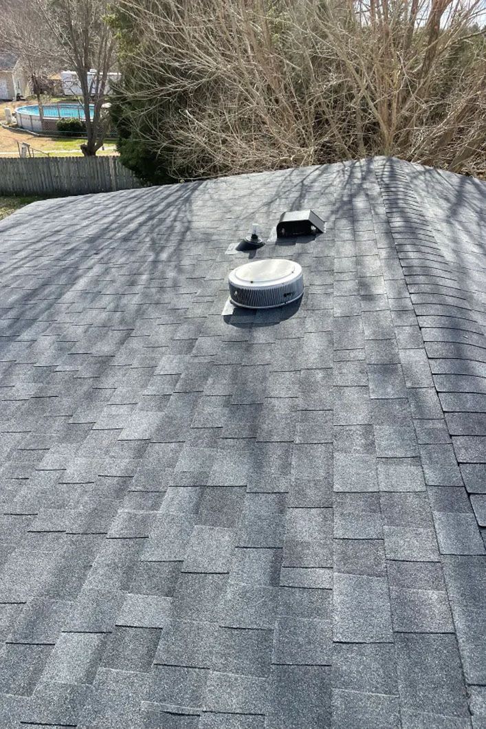 A roof with a chimney on it and trees in the background.