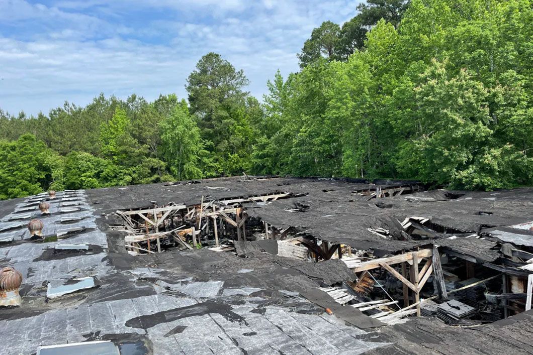 A roof with a lot of damage and trees in the background.