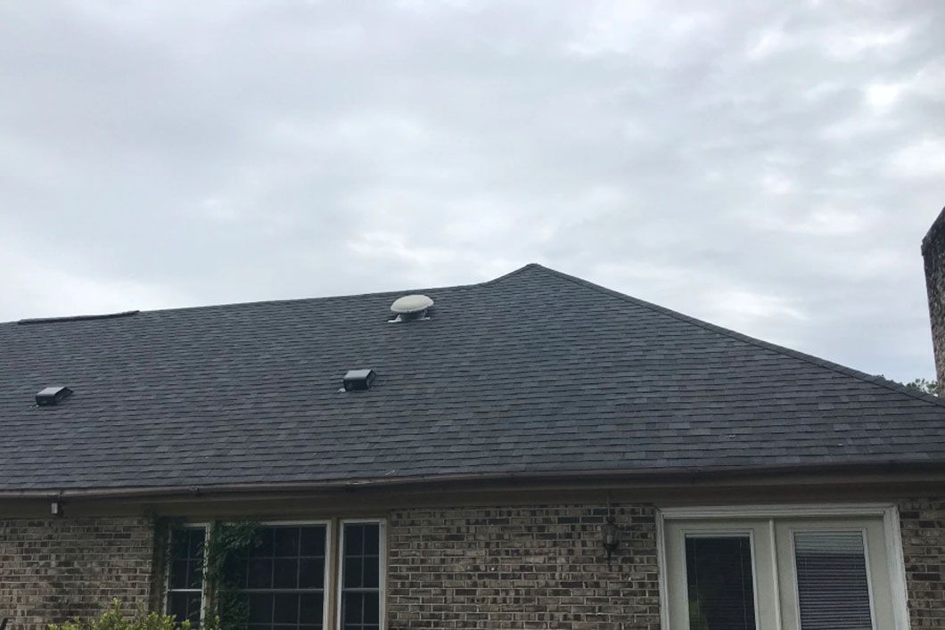 A brick house with a black roof and a chimney.