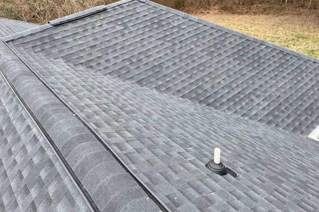 A close up of a roof with shingles and a chimney on it.