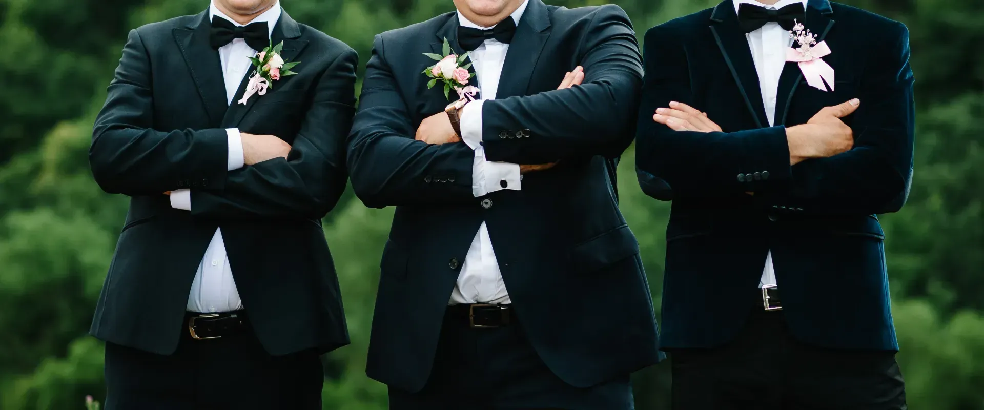 Three men in suits and bow ties are standing next to each other with their arms crossed.