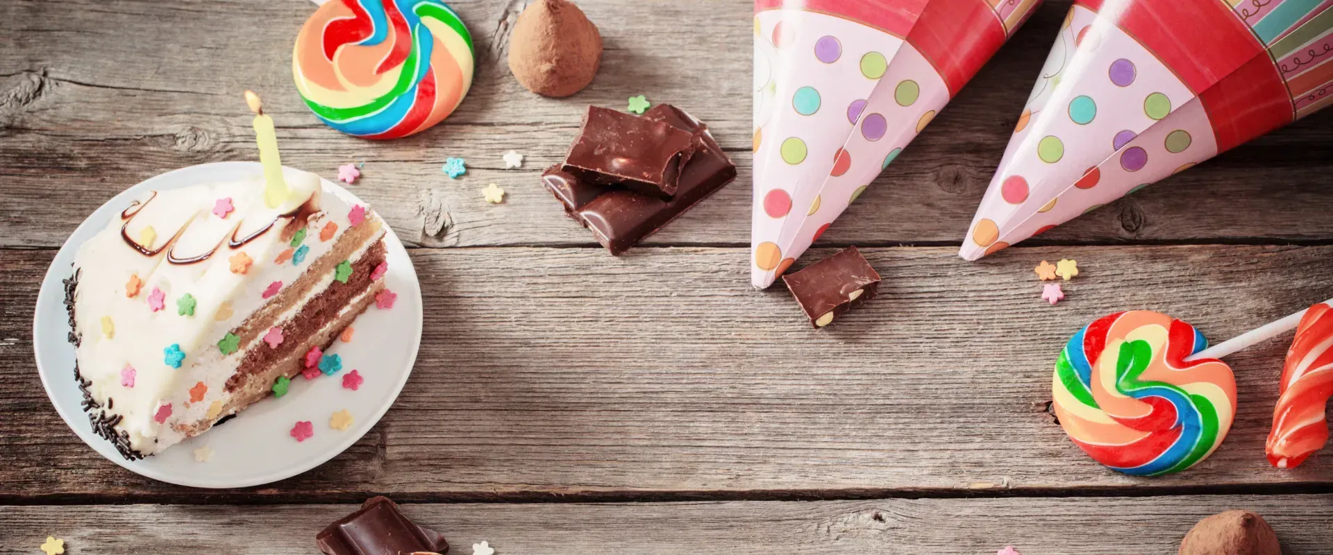 There is a slice of birthday cake on a plate on a wooden table.