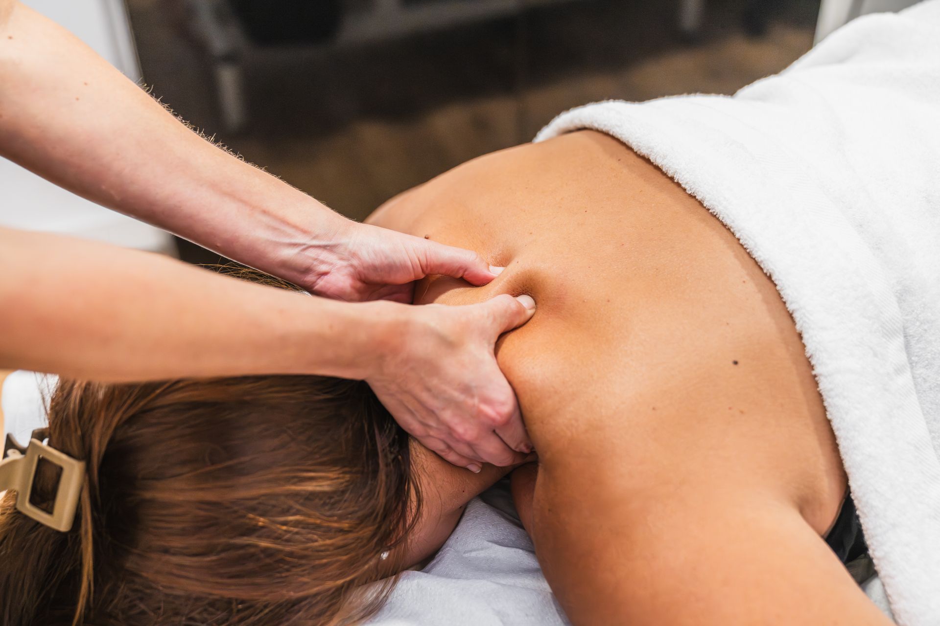 Massage therapist giving a neck and shoulder massage to a reclining person in a spa setting