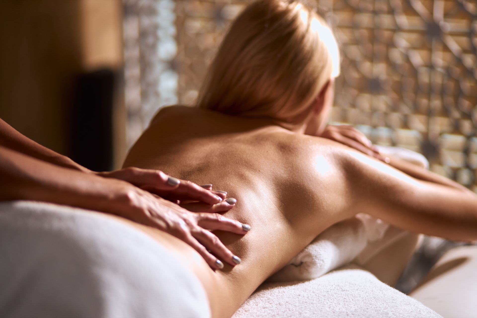 Massage therapist applying back massage to person lying on a spa table