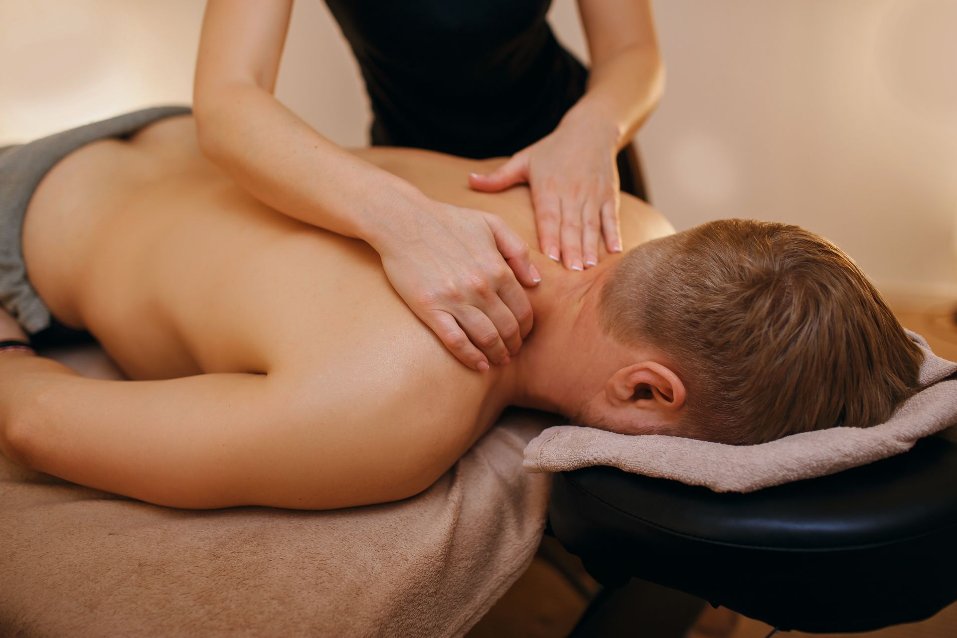 Massage therapist giving a neck and back massage on a treatment table