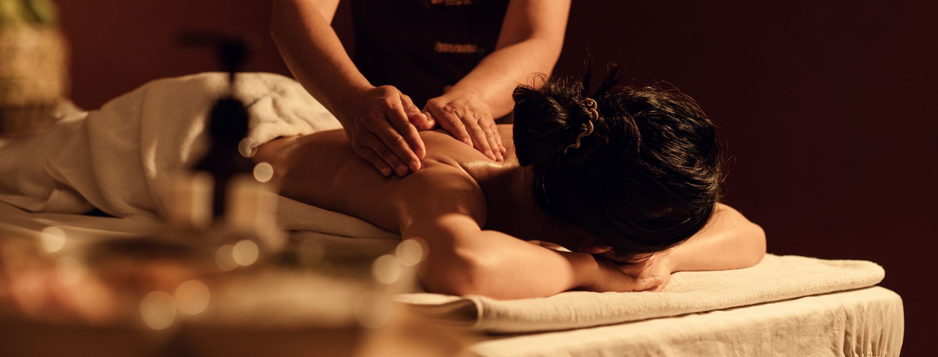 Person receiving a back massage in a warm, dimly lit spa room