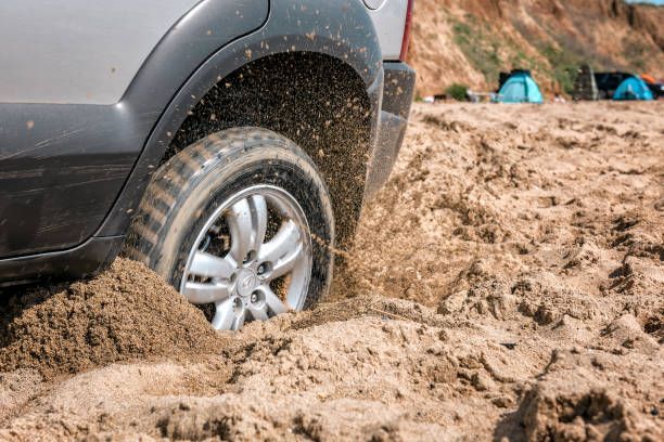 A car is stuck in the sand on a beach.