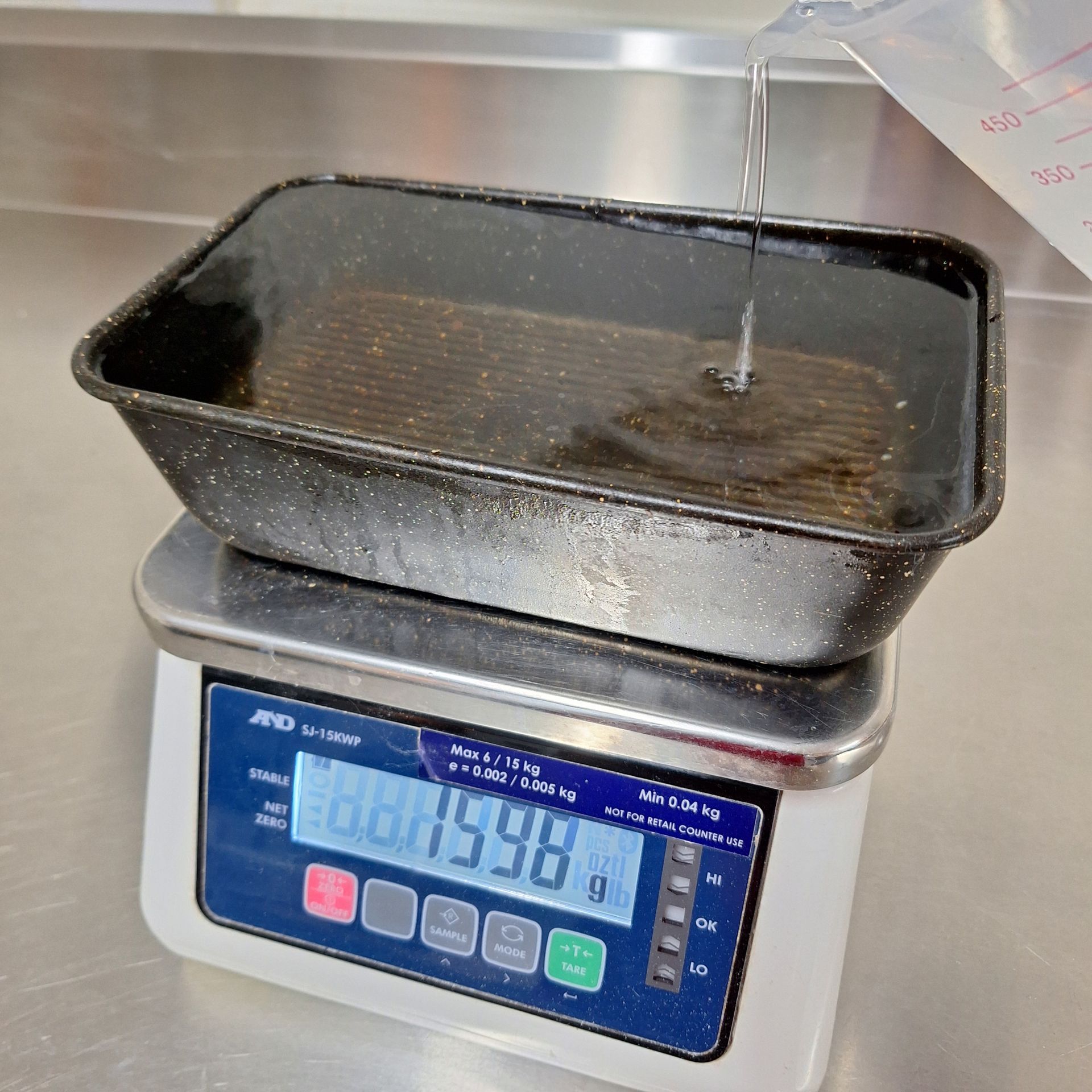 weighing tin with water to calculate loaf tin capacity for dough