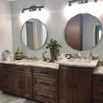 A bathroom with two sinks , two mirrors , and wooden cabinets.