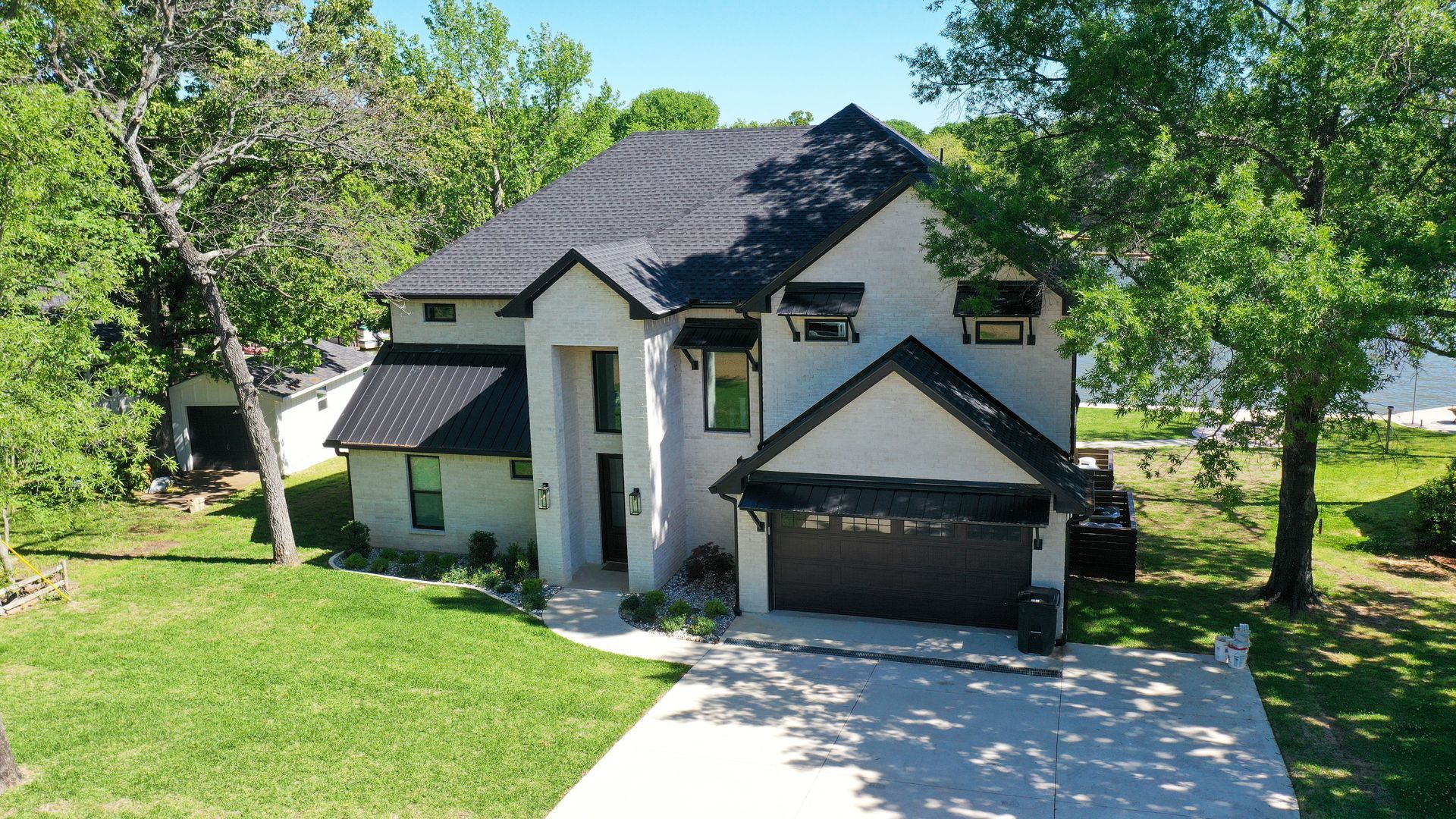 An aerial view of a large white house with a black roof surrounded by trees.