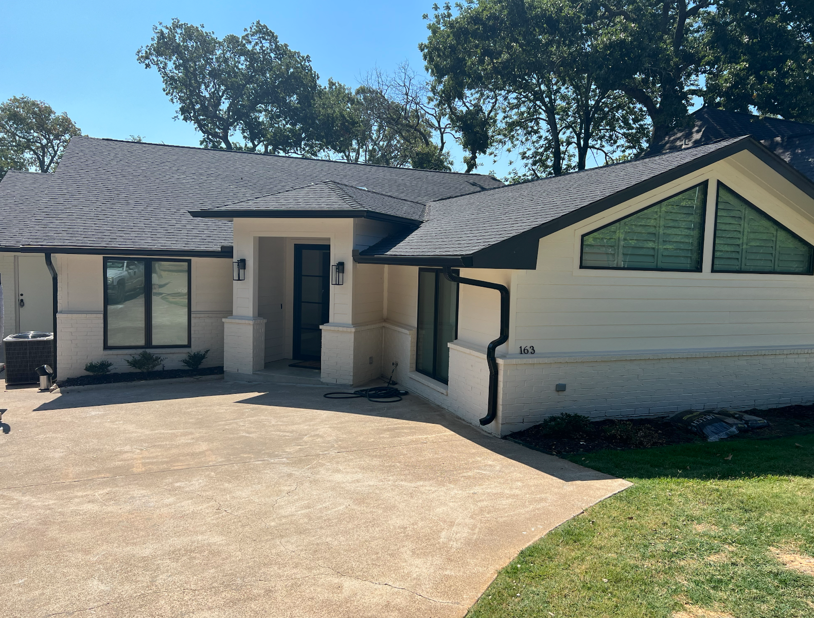 A white house with a black roof and a driveway