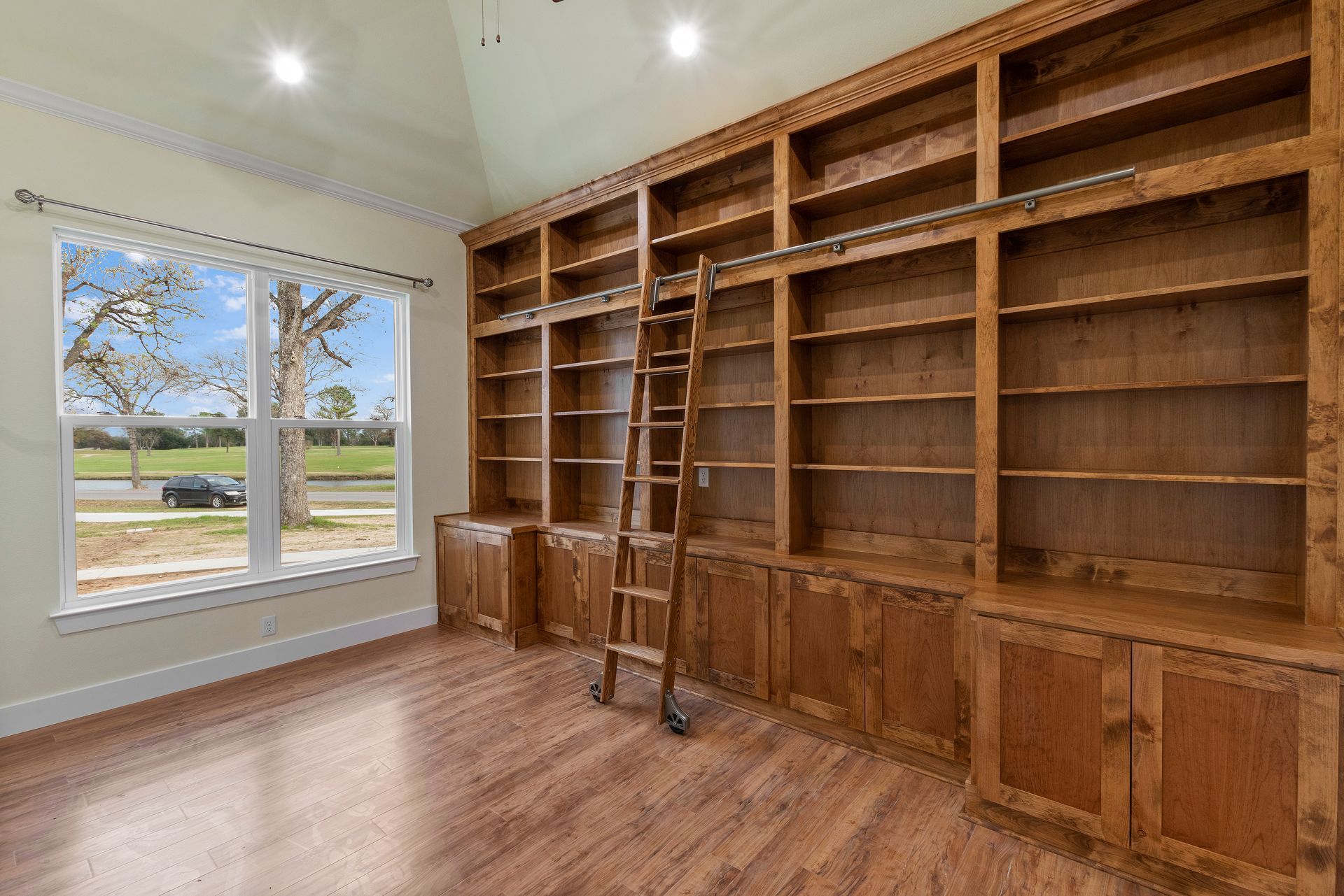 A large empty room with lots of wooden shelves and a ladder.