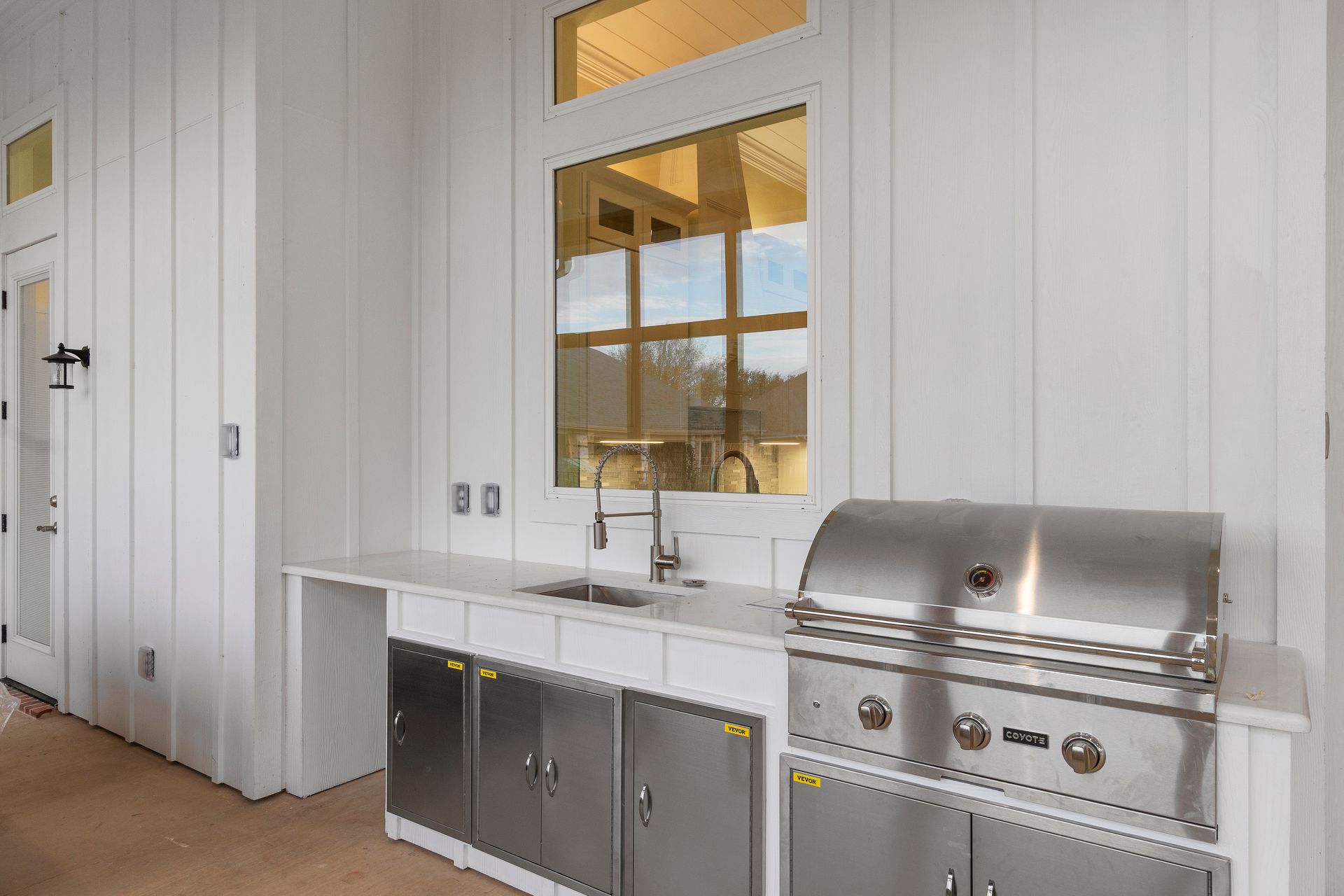 A kitchen with stainless steel cabinets , a sink , and a grill.