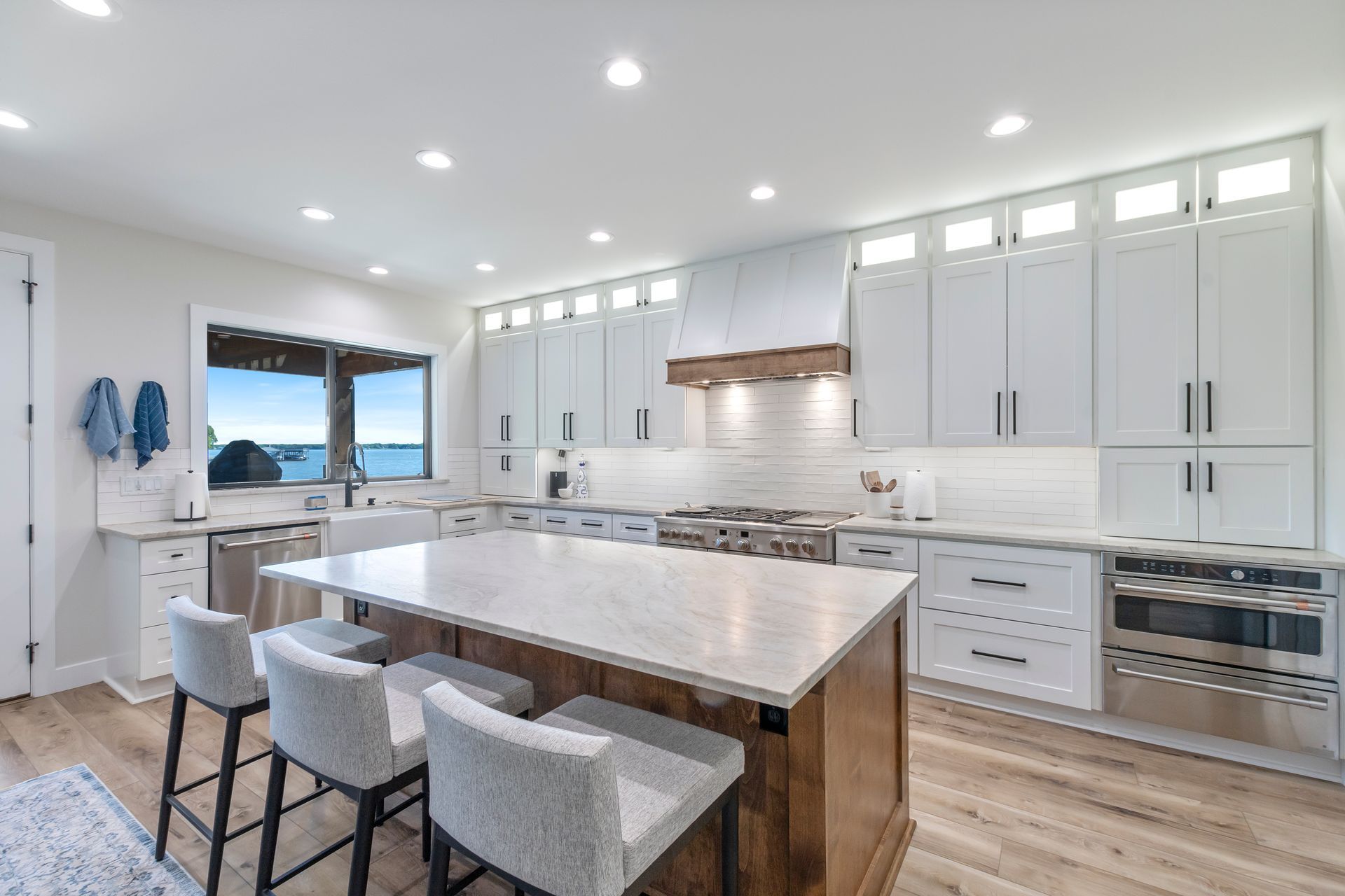 A kitchen with white cabinets and stainless steel appliances and a large island.