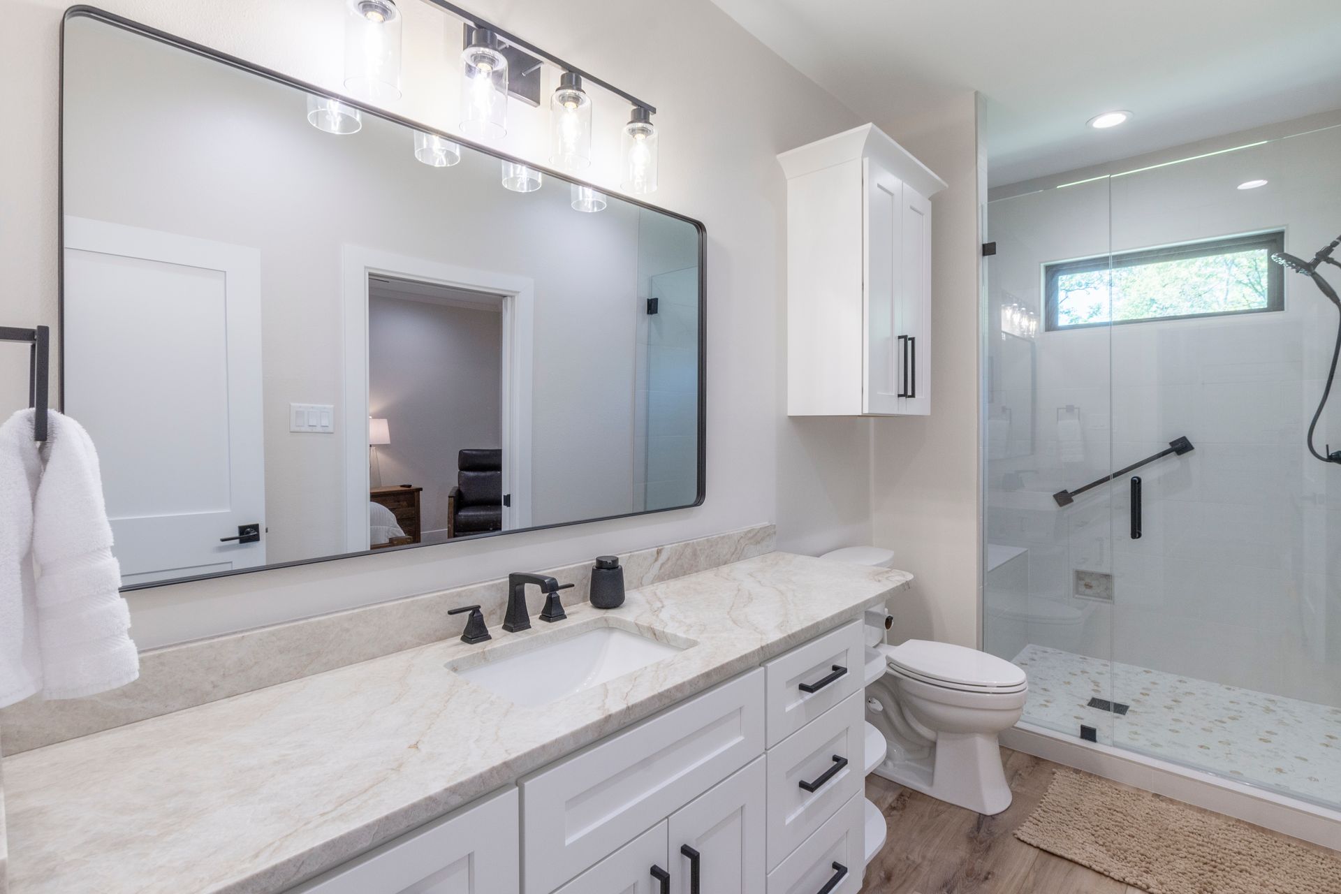 A bathroom with a sink , toilet , shower and mirror.