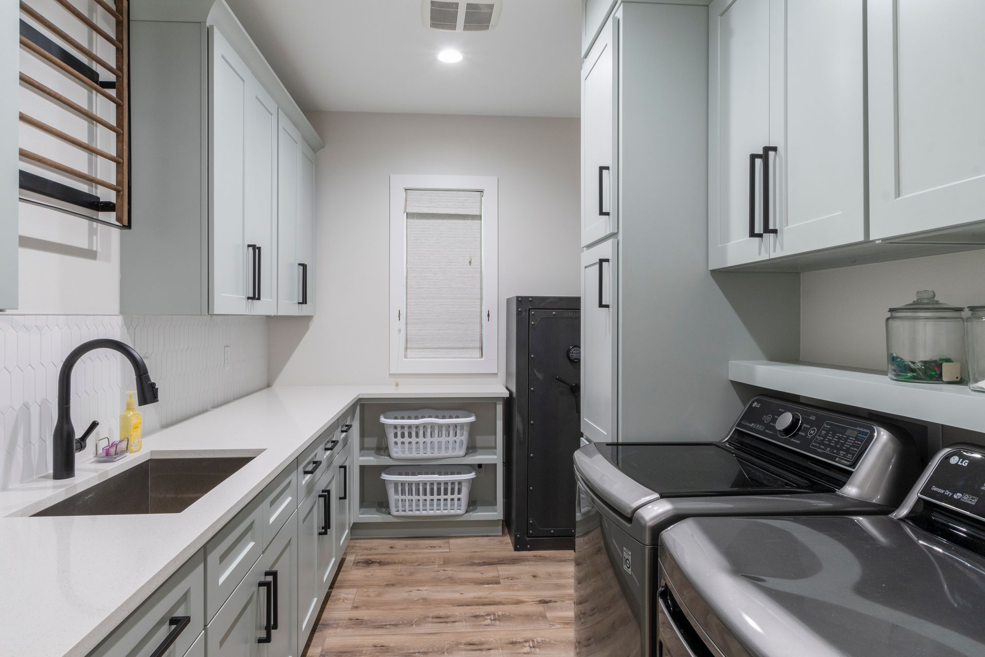 A laundry room with a sink , washer and dryer , and a window.