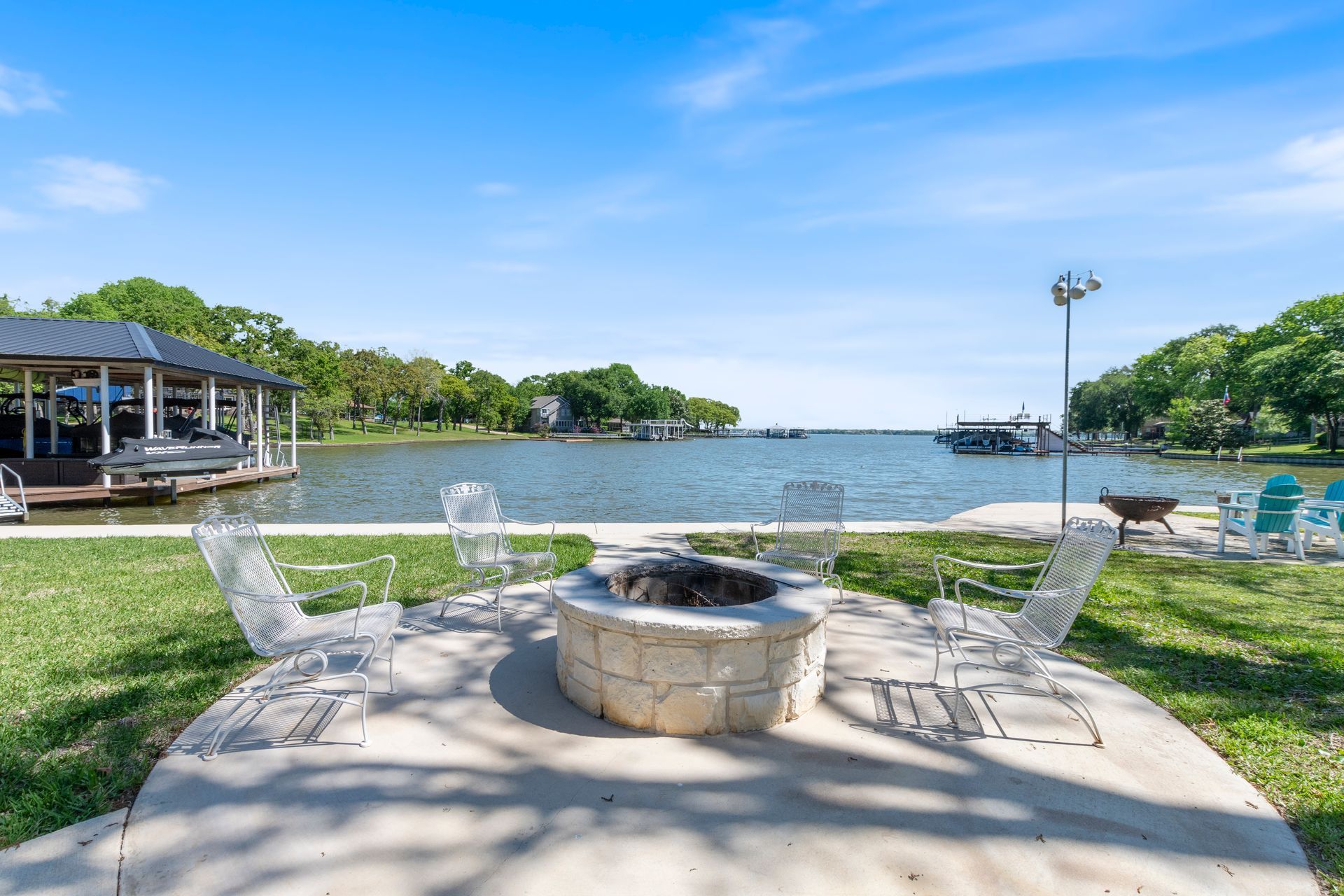 There is a fire pit in the middle of the grass next to a lake.
