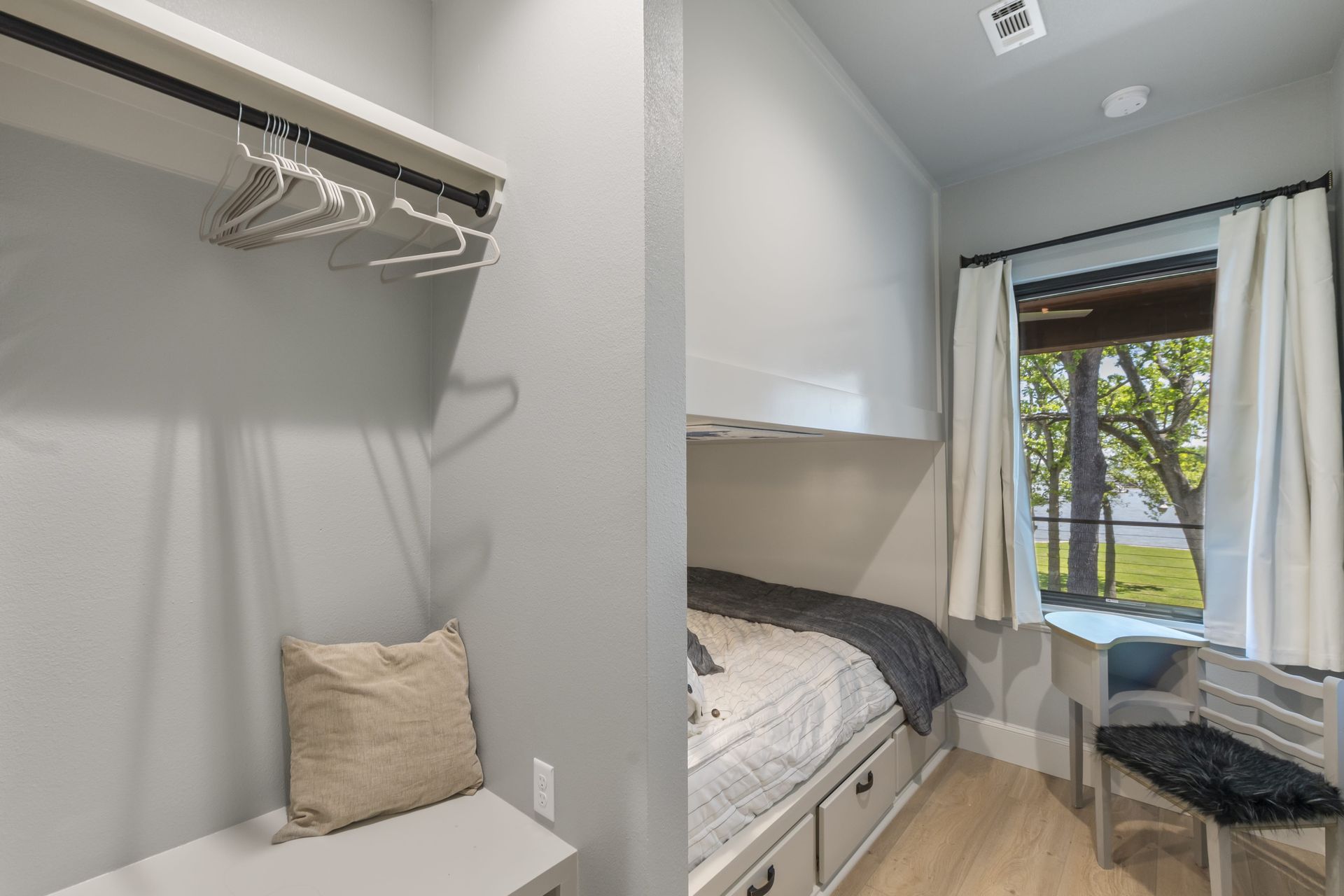A bedroom with a bed , chair , closet and window.