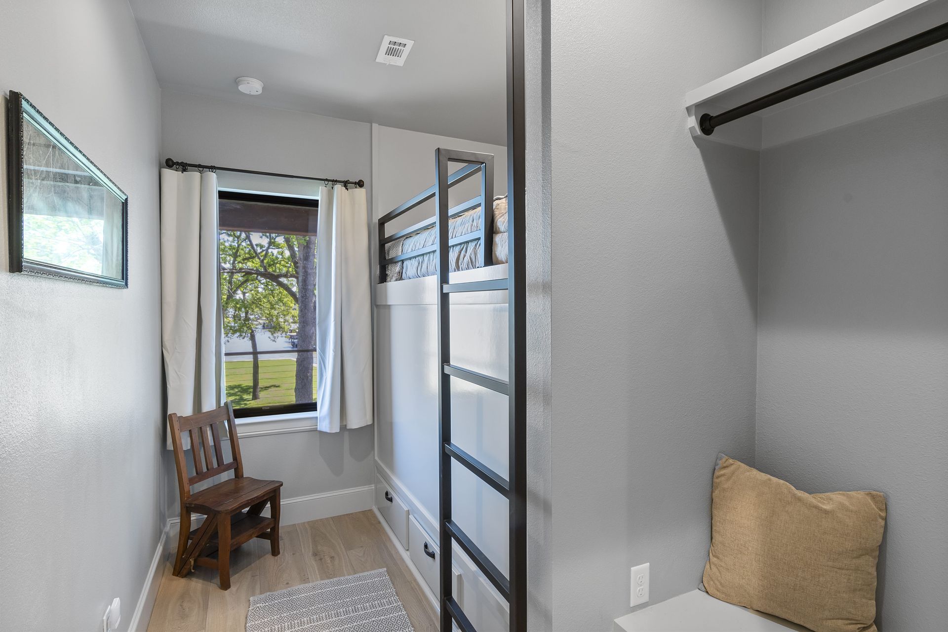 A bedroom with bunk beds , a chair and a ladder.