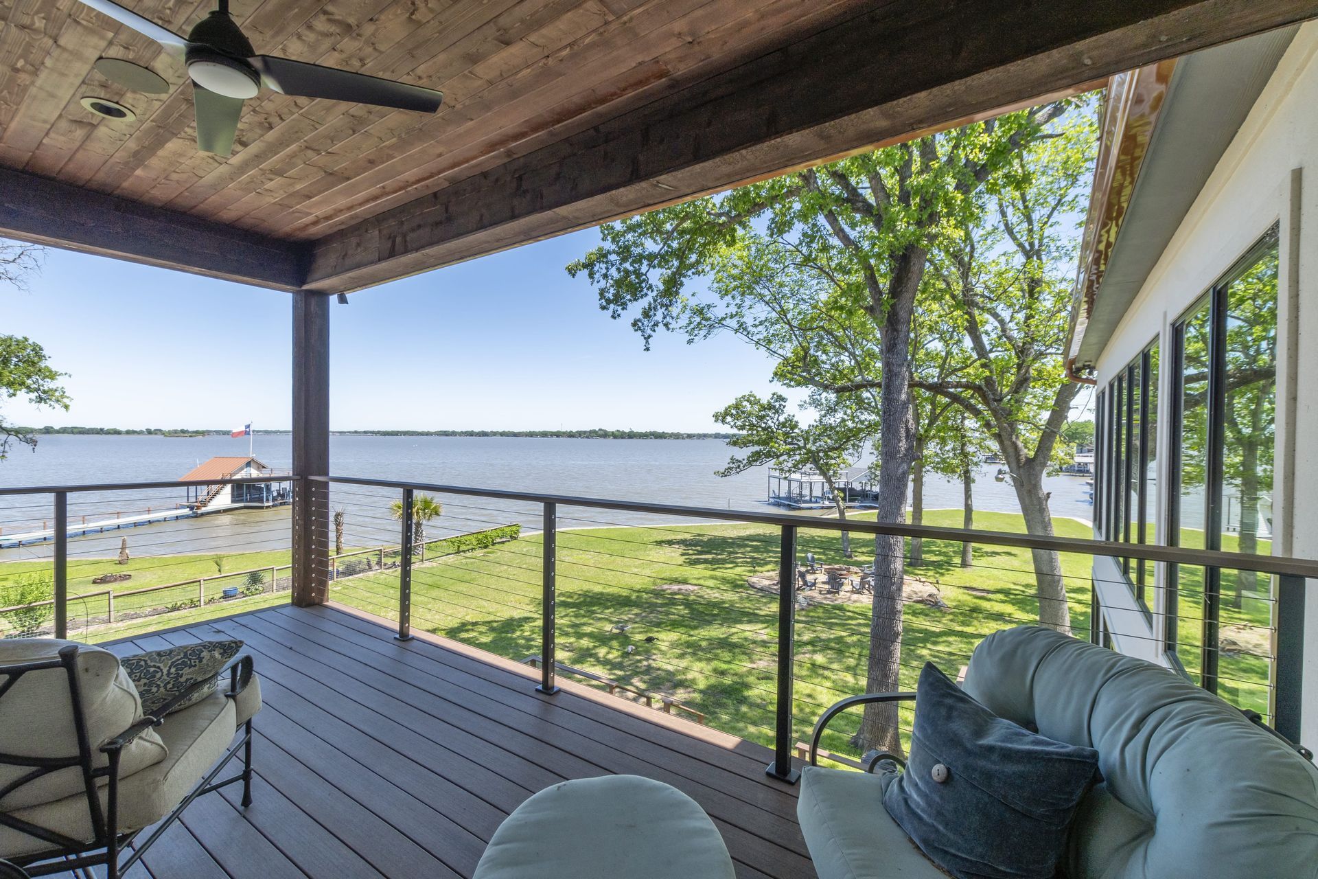 A porch with a view of a lake and a ceiling fan.