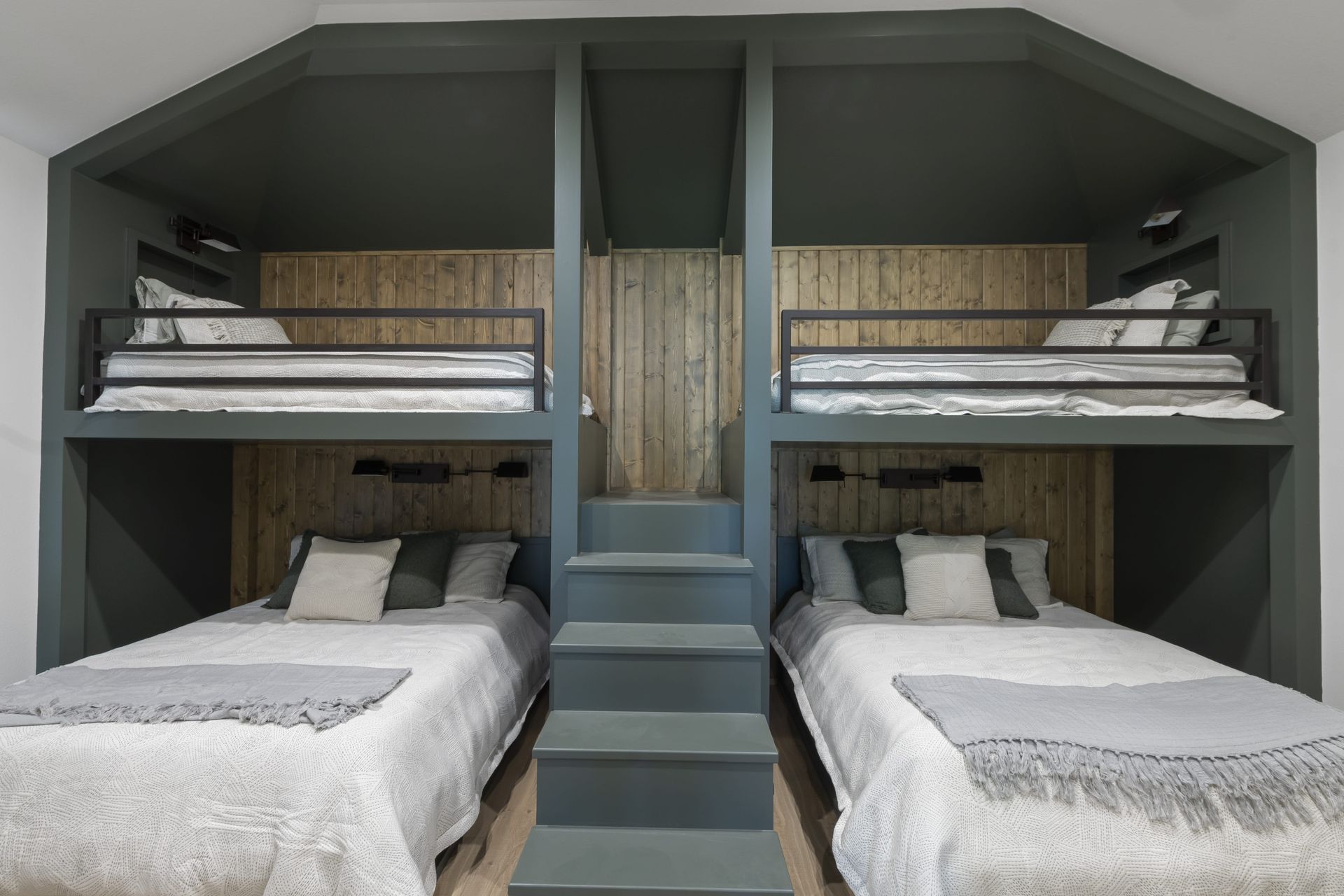 A bedroom with three bunk beds and stairs leading to them.