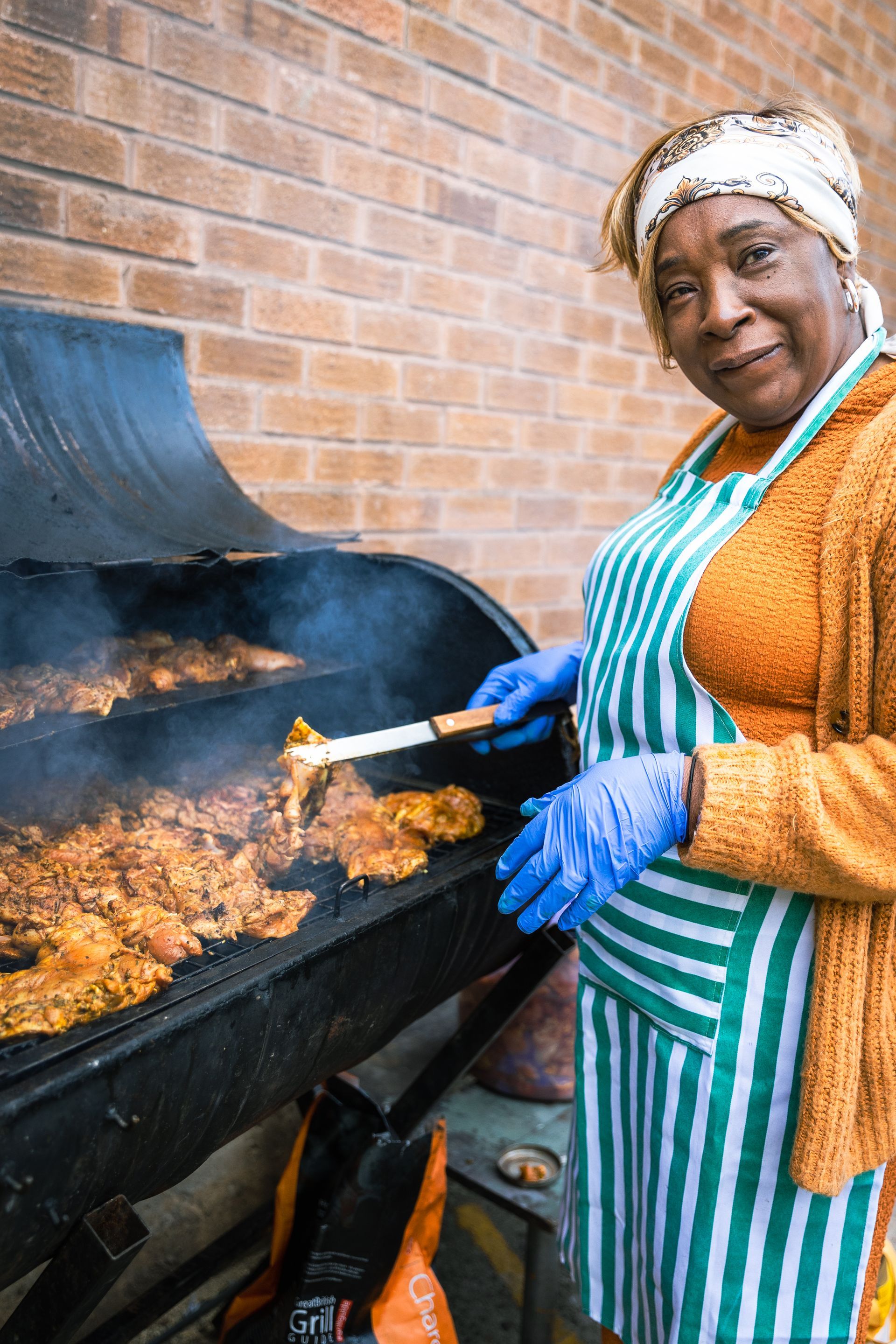 A woman is cooking food on a grill outside.