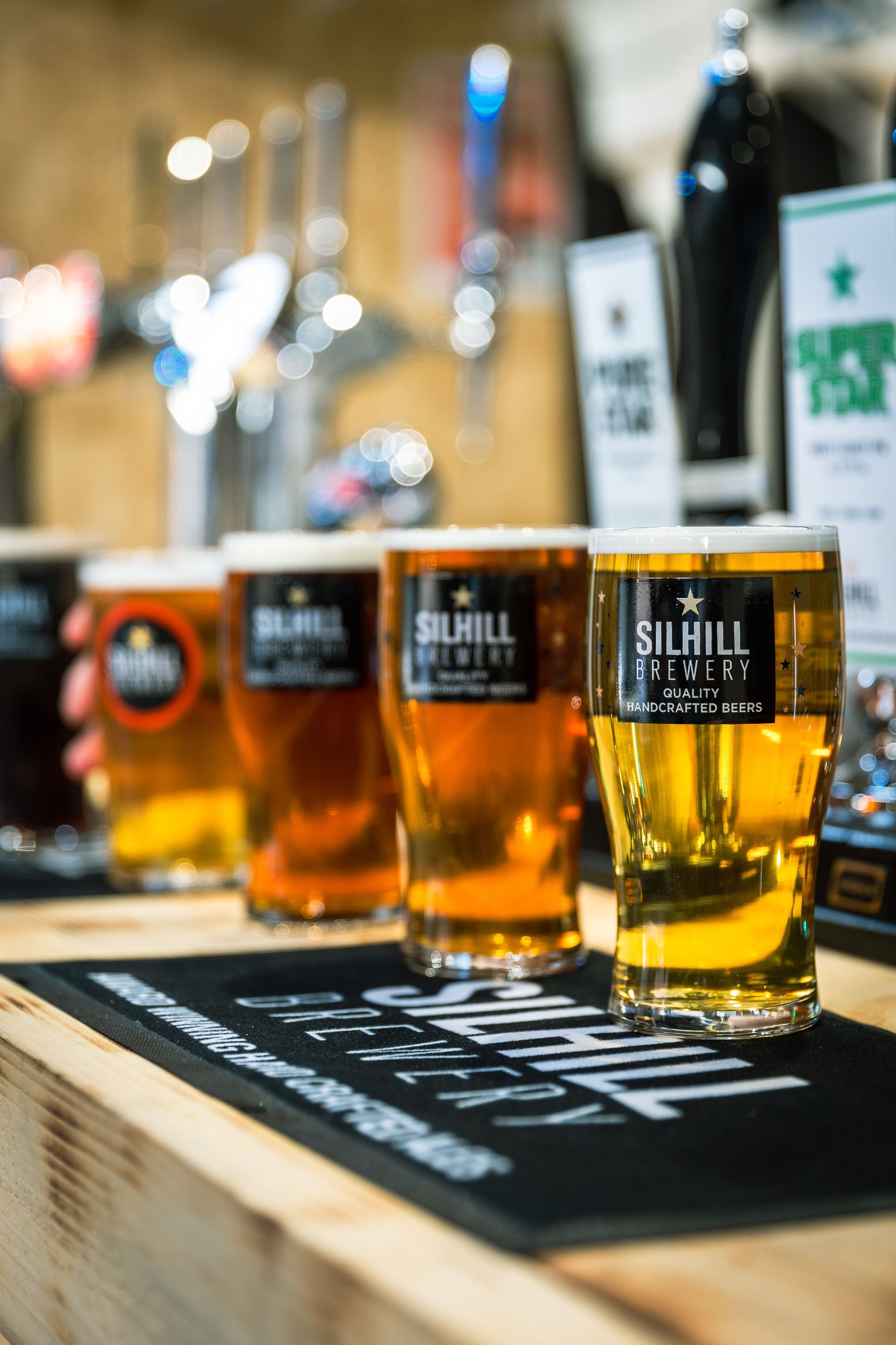 Several glasses of beer are lined up on a bar
