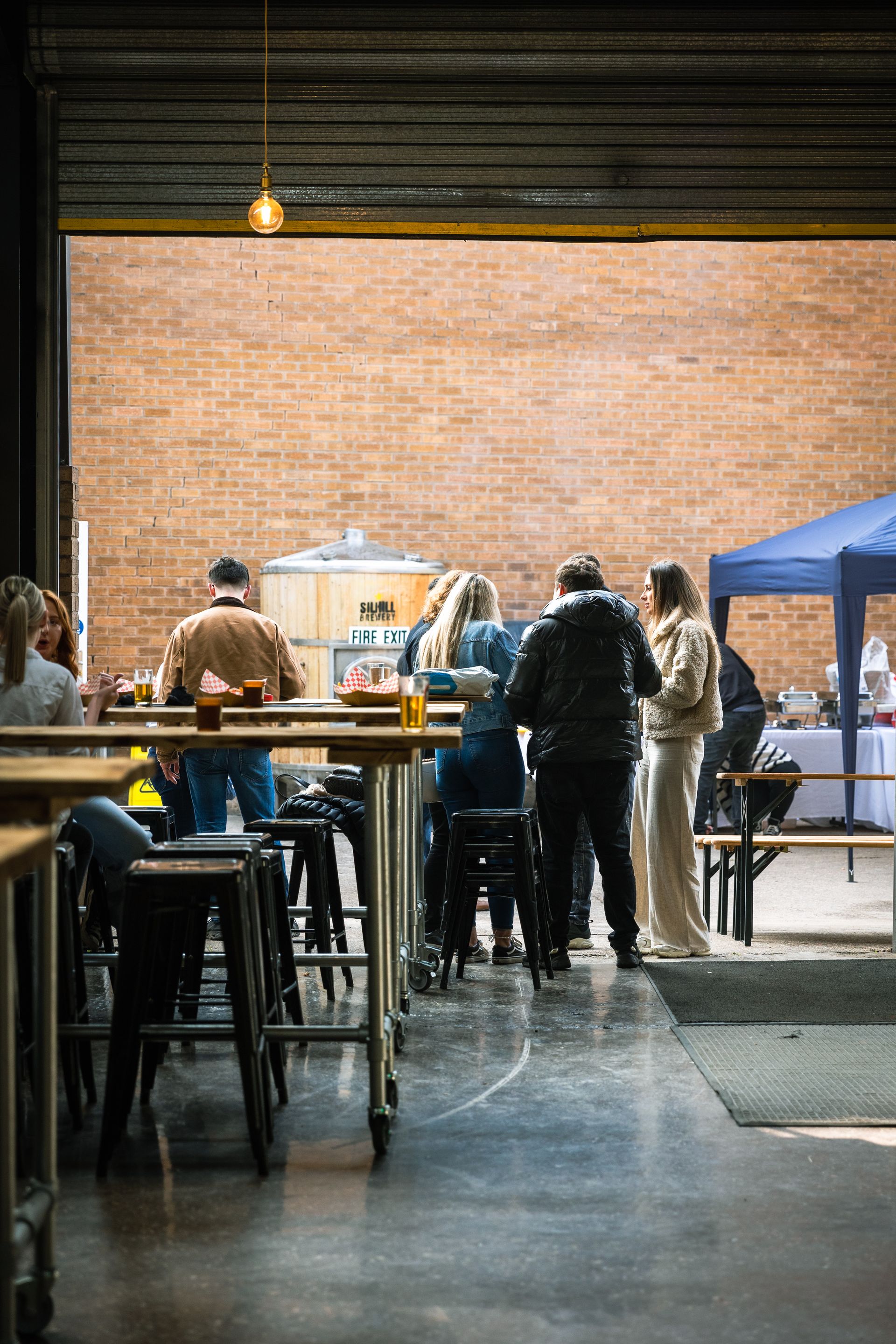 A group of people are standing around tables in a restaurant.