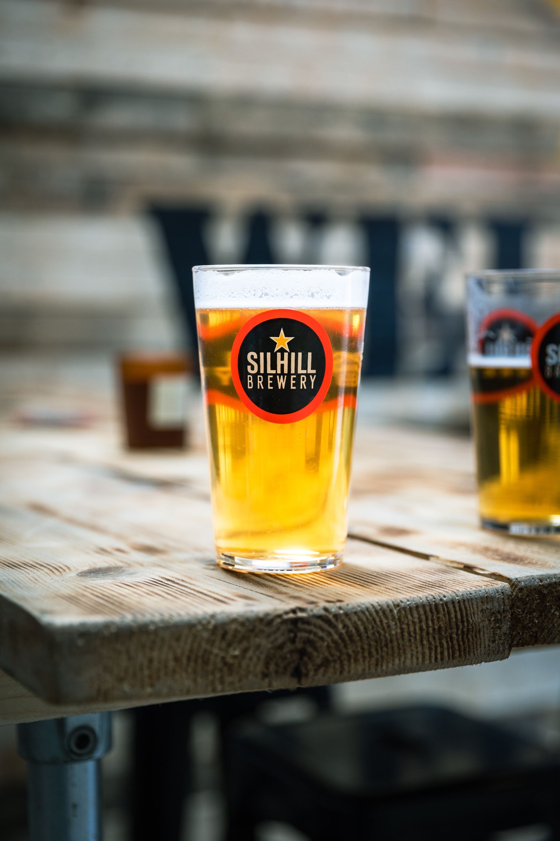 A glass of beer is sitting on a wooden table.