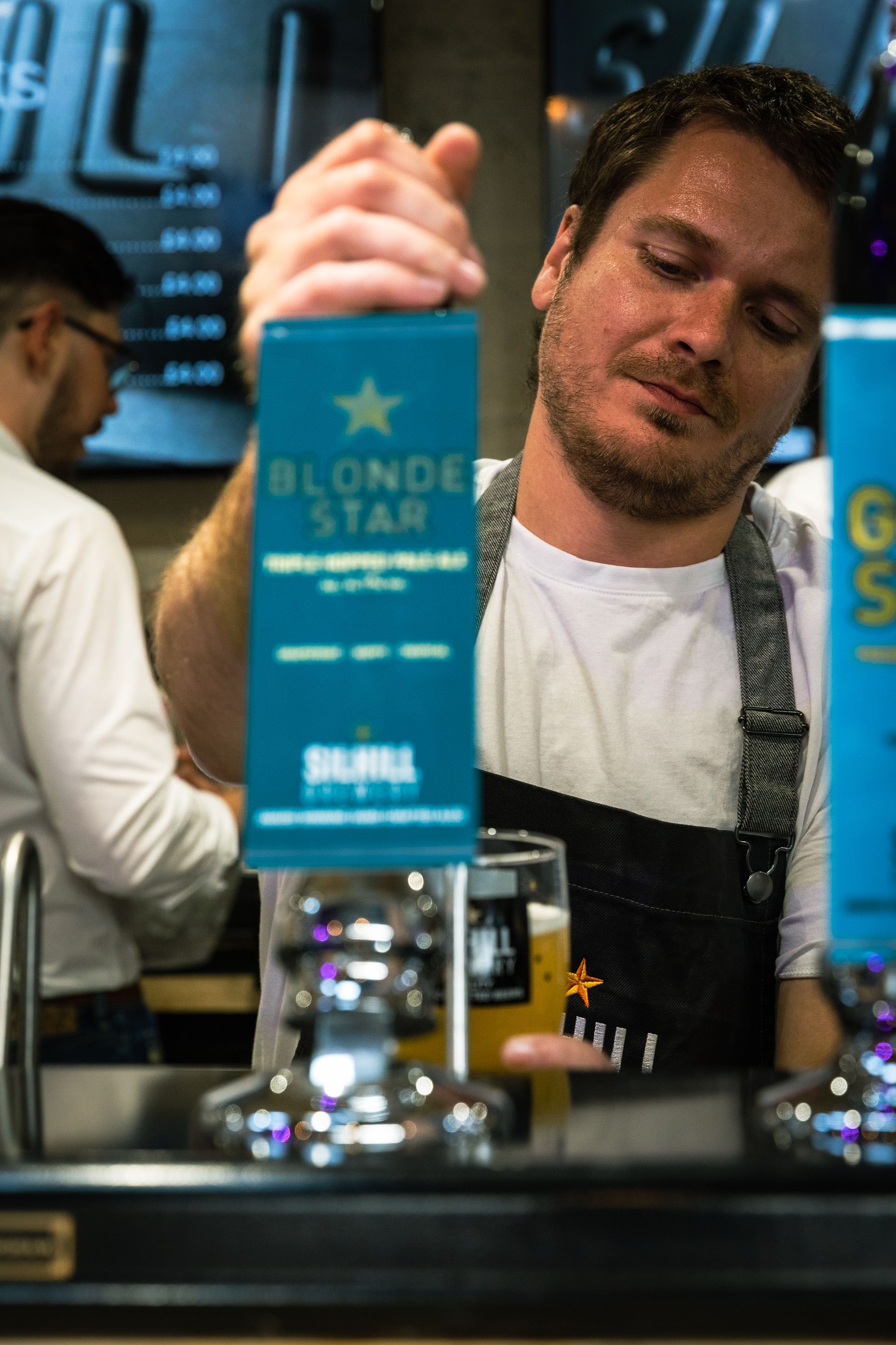 A man is pouring a blonde star beer into a glass