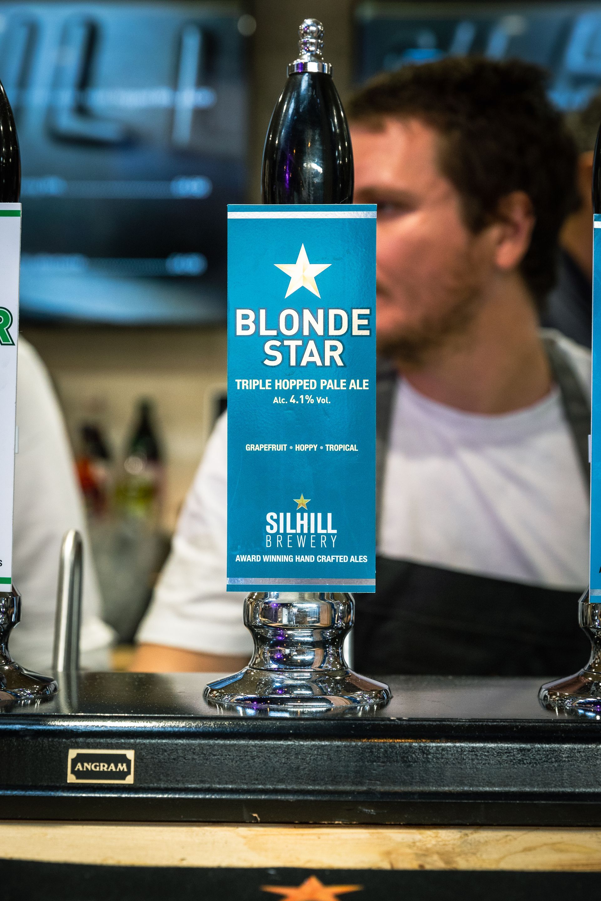 A blonde star beer tap with a man in the background