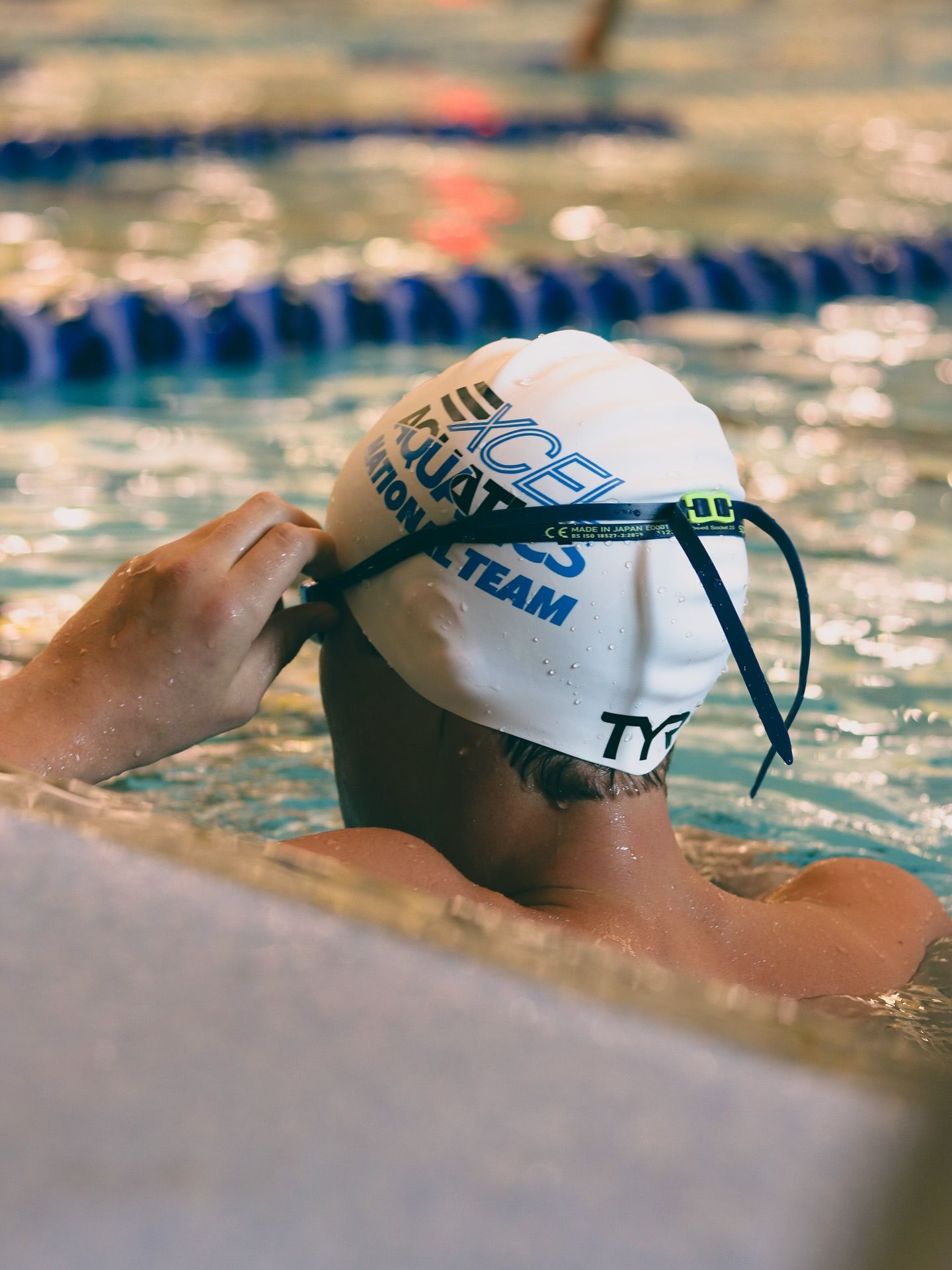 Underwater view of a swimming pool with lane markers, bubbles, and swim fins overhead.