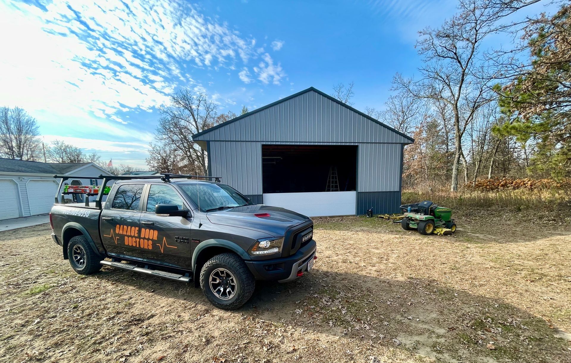 A black truck is parked in front of a barn.