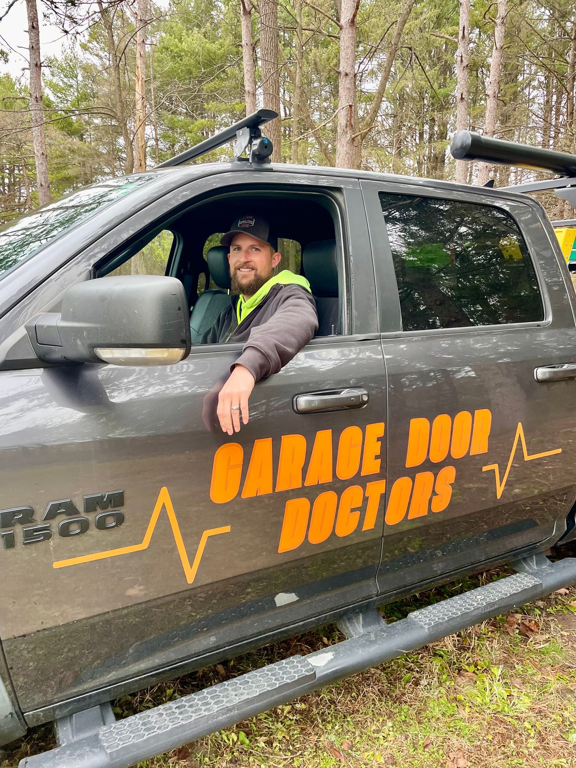 A sign for garage roof doctors is sitting on the side of a road.