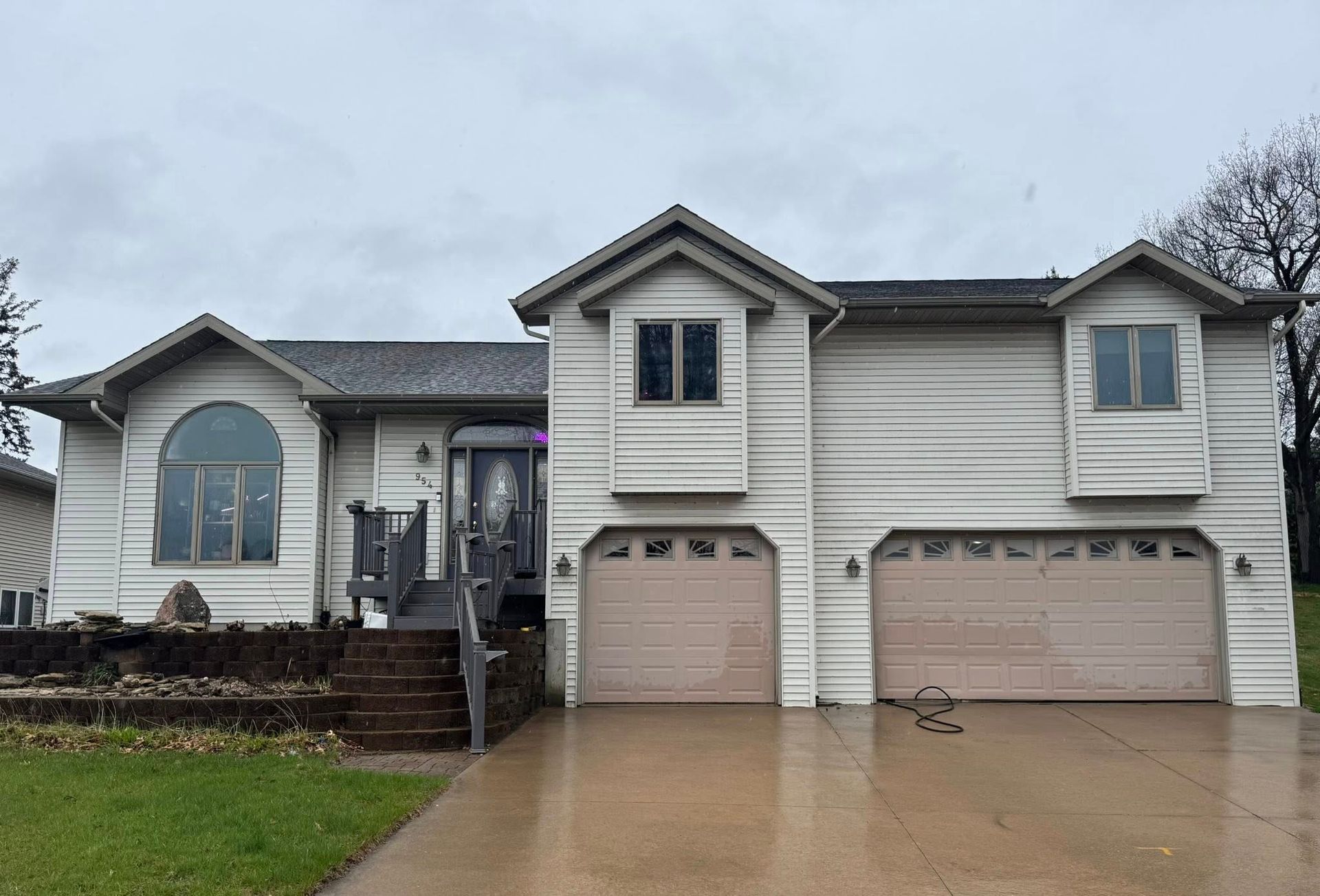 A large white house with two garage doors and a concrete driveway.
