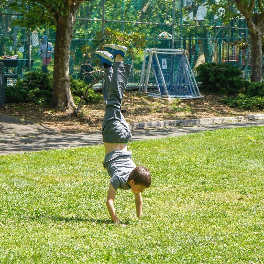 A 5th grader does a handstand in the park during a break from PE class.