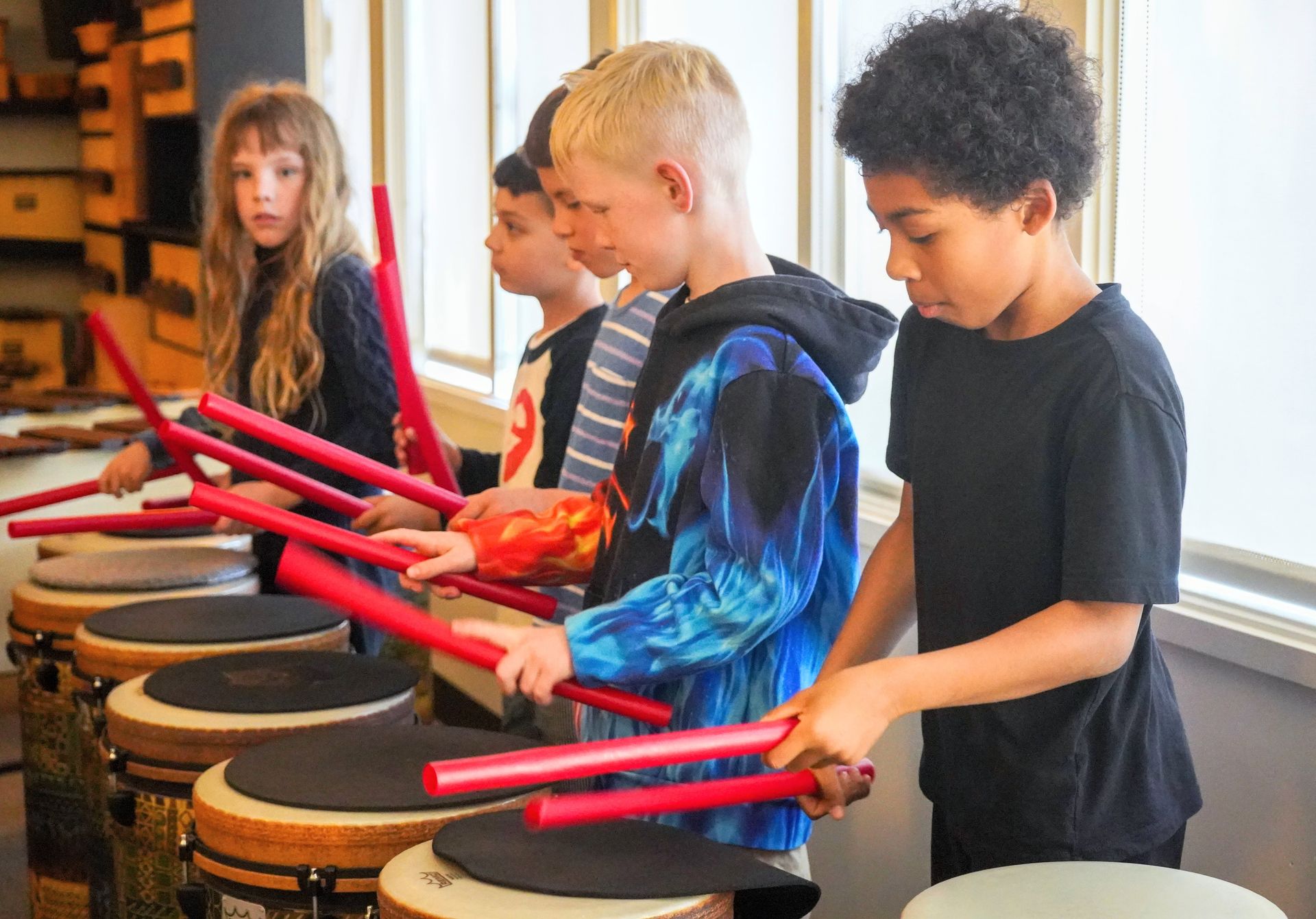 Four Lower Elementary students practice playing the drums in music class.
